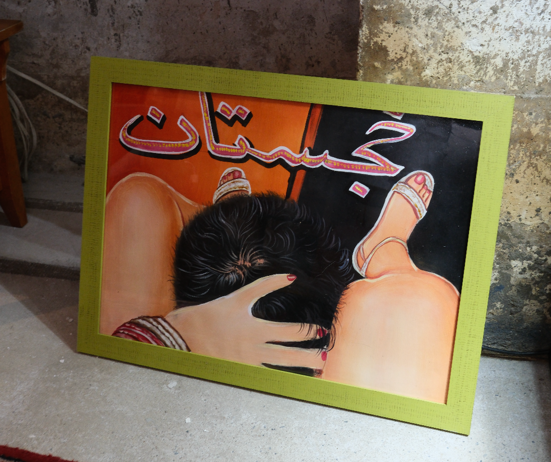 Colorful Khajistan framed artwork on floor with bold Urdu script and expressive figures