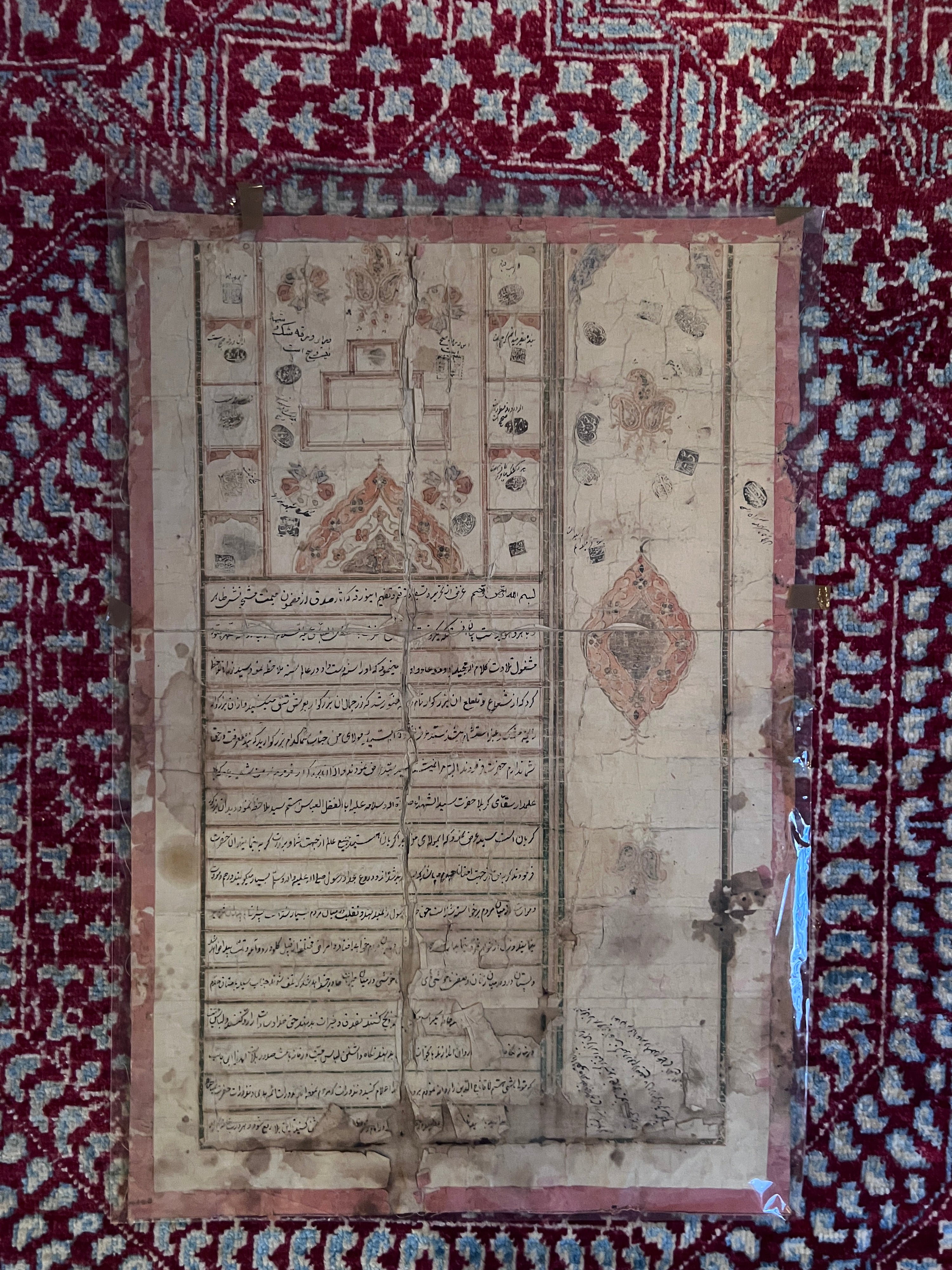 Old Persian document with text and illustrations on a red and white patterned fabric background